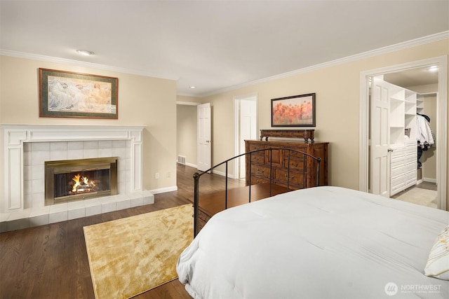 bedroom featuring crown molding, a fireplace, baseboards, and wood finished floors