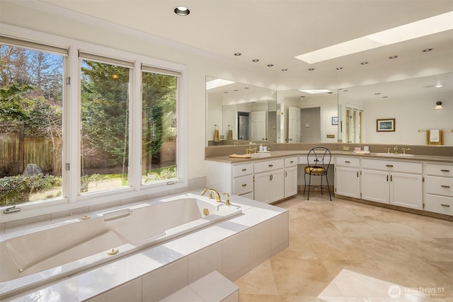 bathroom featuring a skylight, recessed lighting, a tub with jets, and vanity