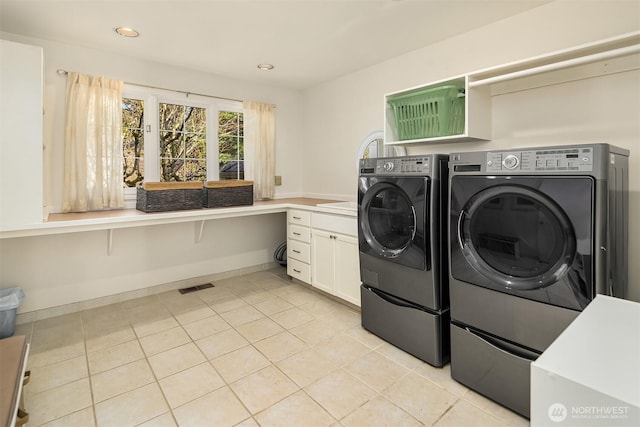 clothes washing area featuring light tile patterned floors, visible vents, baseboards, independent washer and dryer, and cabinet space