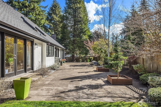 view of patio featuring a garden, a fenced backyard, and a grill