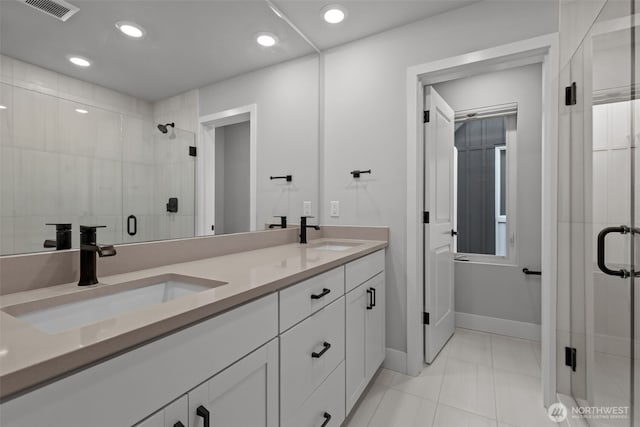 full bath with a sink, visible vents, a stall shower, and double vanity