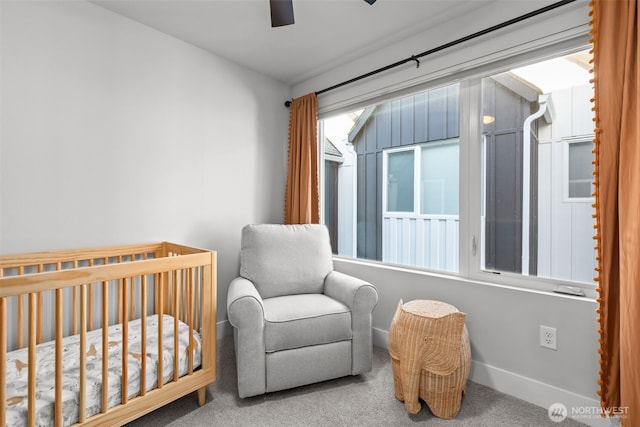 carpeted bedroom featuring a crib, baseboards, and ceiling fan