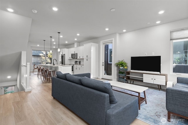 living area featuring light wood-style flooring, recessed lighting, and baseboards