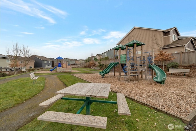 community jungle gym featuring a residential view, a yard, and fence