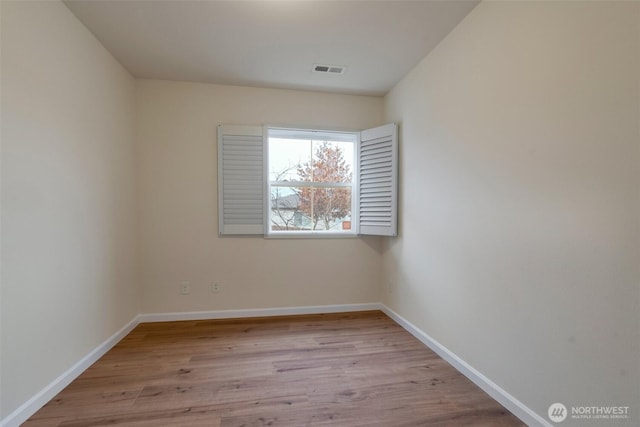 spare room with visible vents, baseboards, and wood finished floors