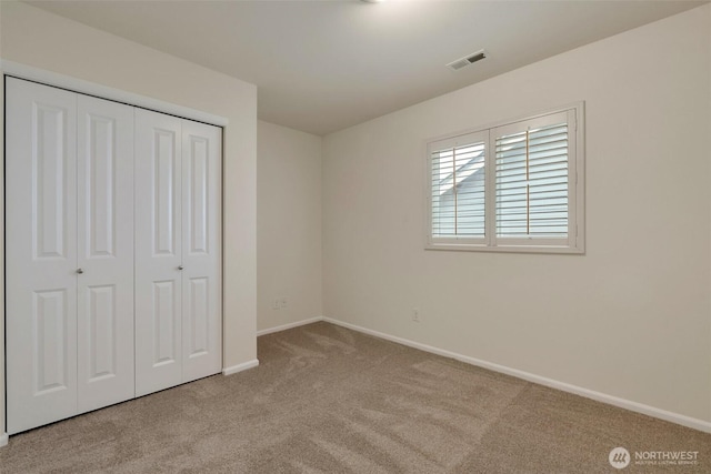 unfurnished bedroom featuring visible vents, carpet, a closet, and baseboards