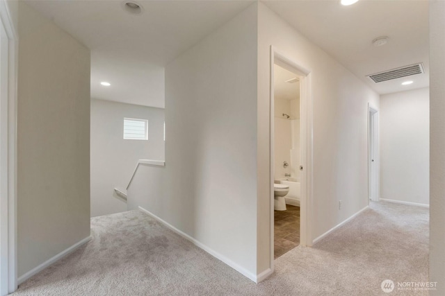 hallway featuring carpet, visible vents, baseboards, recessed lighting, and an upstairs landing