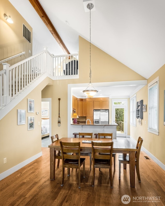 dining area featuring beam ceiling, visible vents, stairway, wood finished floors, and baseboards