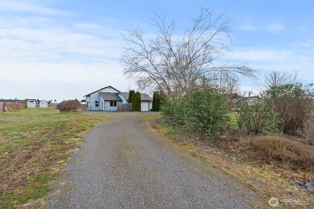 view of front of house featuring a front lawn, driveway, and fence