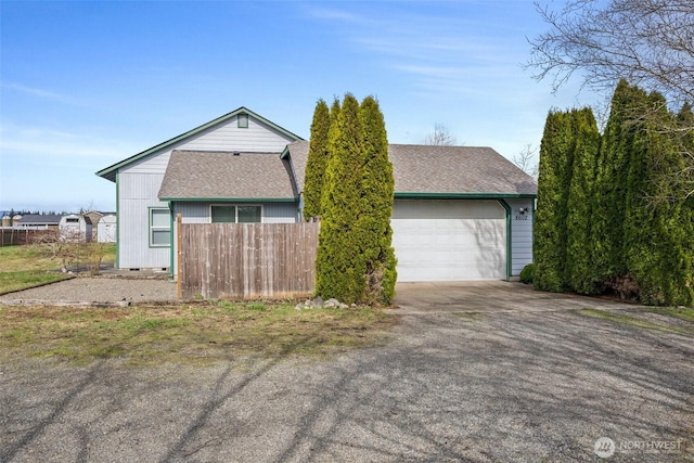 view of front facade featuring a garage, fence, driveway, and a shingled roof