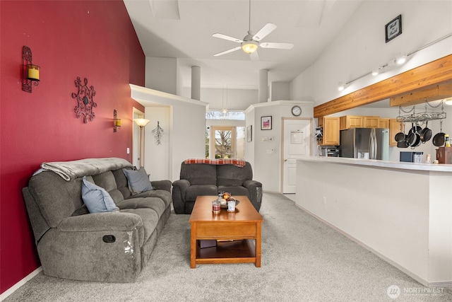 living room featuring light colored carpet, baseboards, and a ceiling fan