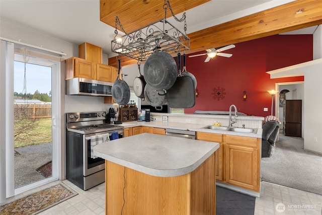 kitchen featuring a sink, a kitchen island, stainless steel appliances, a peninsula, and light countertops