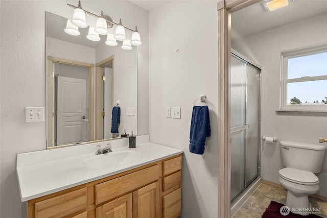 bathroom featuring visible vents, toilet, stone finish floor, a shower stall, and vanity