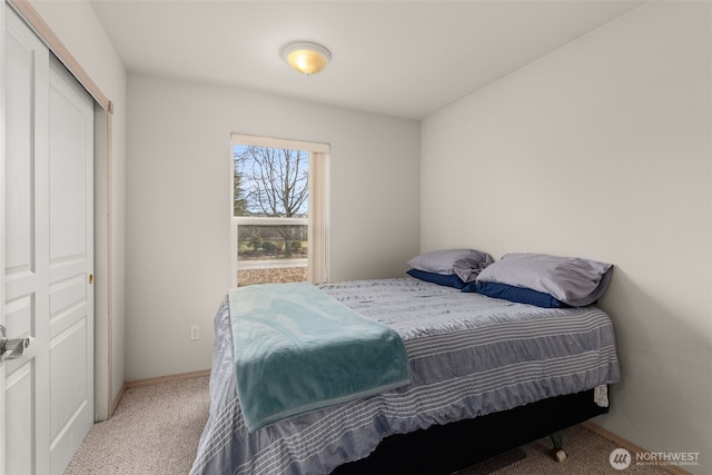 carpeted bedroom featuring a closet and baseboards