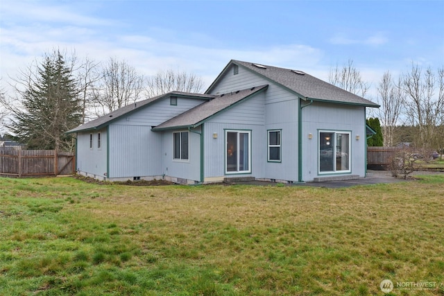 back of property featuring a lawn, a shingled roof, and fence