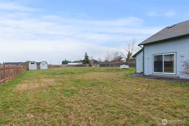 view of yard with an outdoor structure, a fenced backyard, and a shed