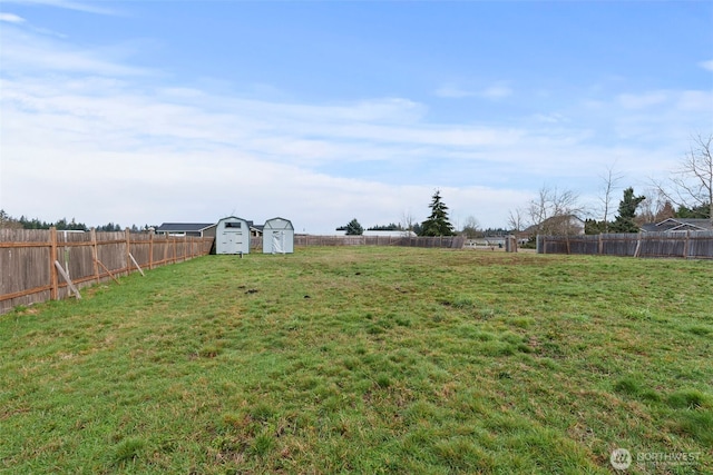 view of yard featuring a storage unit, an outdoor structure, and a fenced backyard