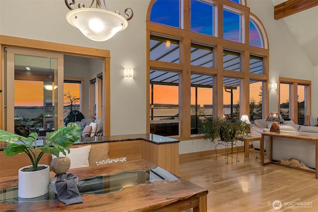 interior space featuring beam ceiling, a towering ceiling, and wood finished floors