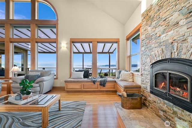 sunroom / solarium with lofted ceiling and a stone fireplace