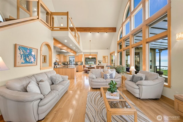 living area with a towering ceiling and light wood-style floors