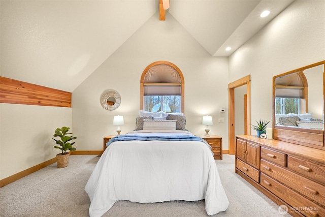 bedroom with beam ceiling, light carpet, baseboards, and multiple windows