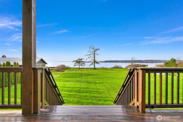 wooden terrace featuring a water view and a lawn