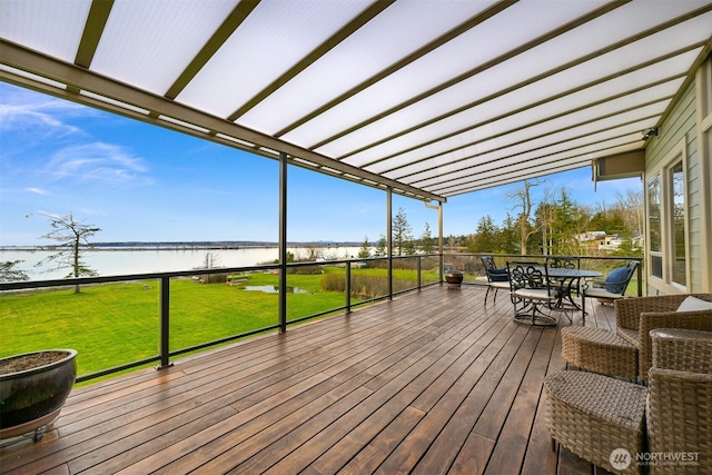 deck featuring outdoor dining space, a lawn, and a water view