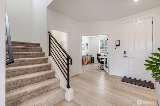 foyer entrance with stairs and light wood-style flooring