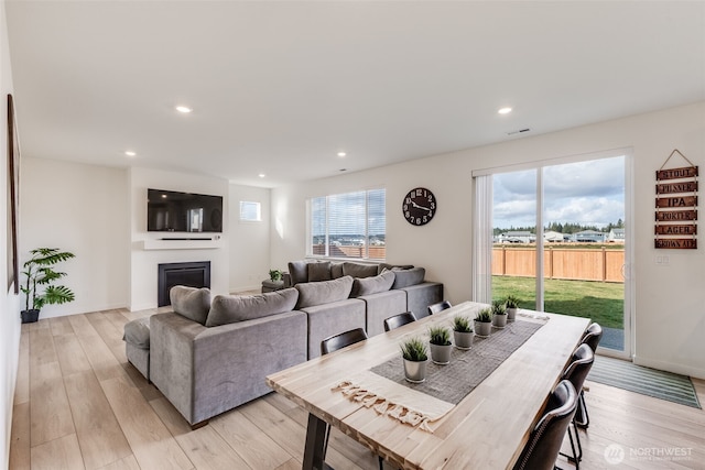 living room with light wood finished floors, recessed lighting, baseboards, and a glass covered fireplace