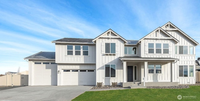 view of front of property with board and batten siding, driveway, a front yard, and fence