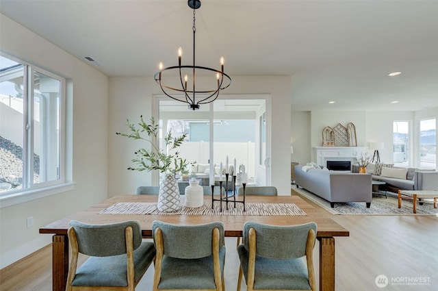 dining space featuring recessed lighting, light wood-style floors, a fireplace, baseboards, and a chandelier