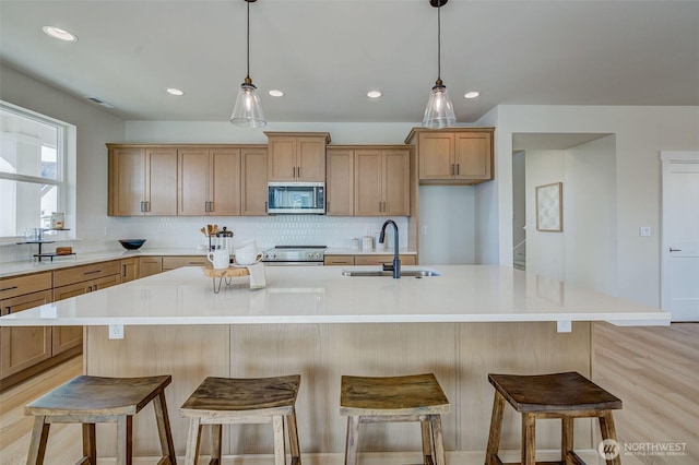 kitchen with a sink, light countertops, tasteful backsplash, and stainless steel appliances