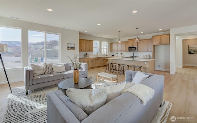 living room with recessed lighting, light wood-style floors, and baseboards