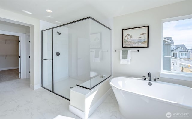 full bathroom with a shower stall, a walk in closet, baseboards, a soaking tub, and marble finish floor