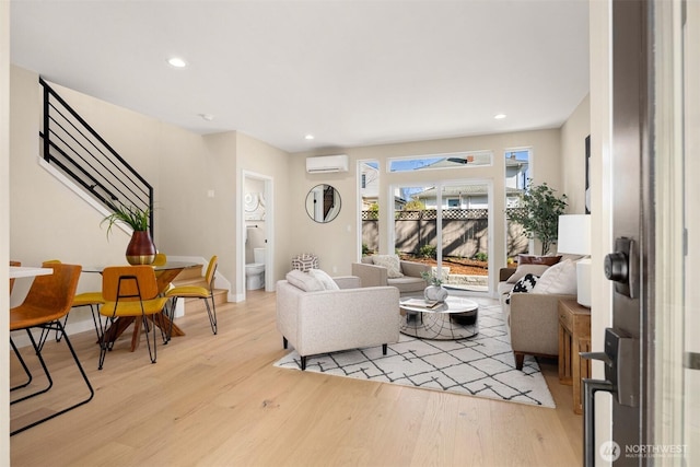 living area featuring recessed lighting, a wall mounted AC, light wood-style floors, baseboards, and stairs