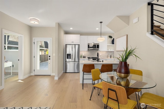 kitchen with stainless steel appliances, white cabinetry, light countertops, decorative backsplash, and open shelves