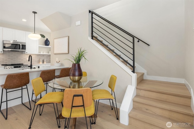 dining room with light wood finished floors, stairs, baseboards, and recessed lighting