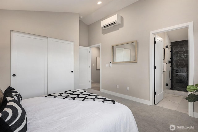 bedroom with ensuite bathroom, a wall unit AC, baseboards, vaulted ceiling, and a closet