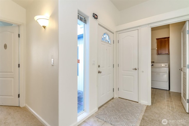 foyer featuring washer / clothes dryer, light tile patterned flooring, and baseboards