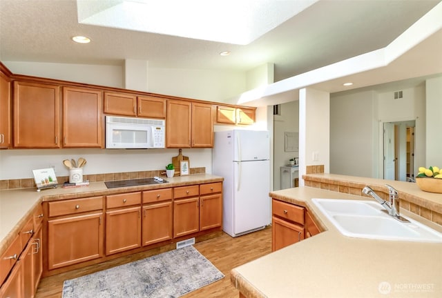 kitchen featuring recessed lighting, white appliances, a sink, light wood-style floors, and light countertops