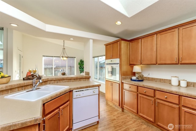 kitchen with white appliances, light wood-style flooring, a sink, and recessed lighting