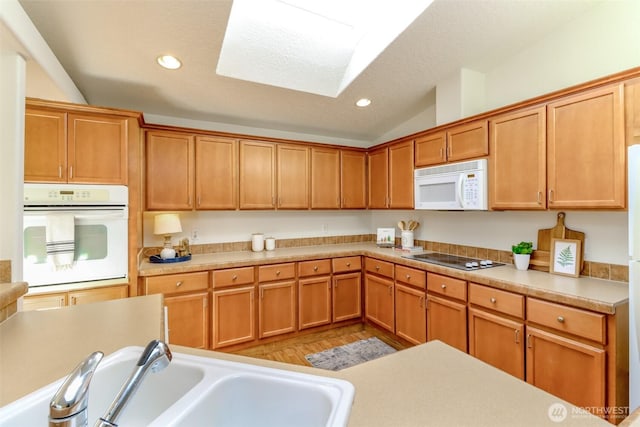 kitchen featuring recessed lighting, light countertops, vaulted ceiling, a sink, and white appliances