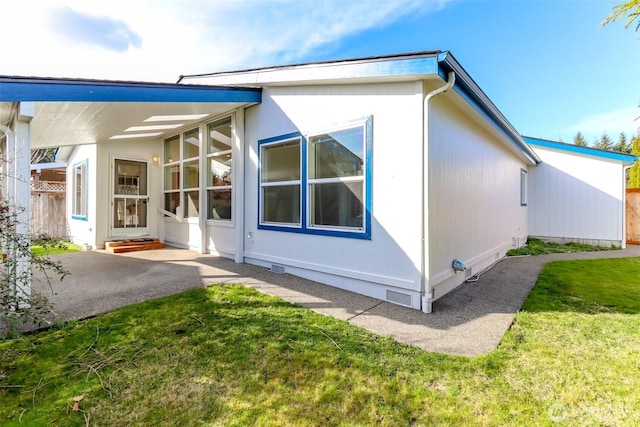 view of side of property with a patio, crawl space, and a lawn