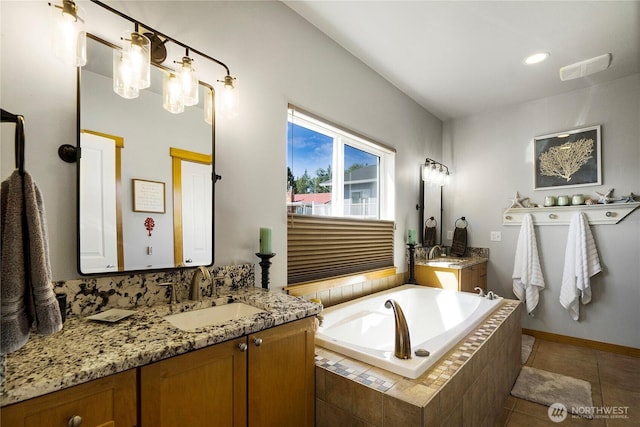 full bath featuring tile patterned flooring, a garden tub, two vanities, and a sink