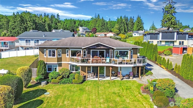 rear view of property with a residential view, a lawn, and a patio