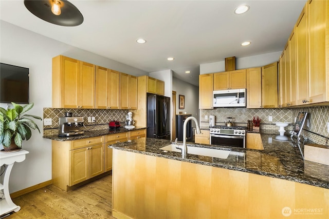 kitchen featuring a sink, freestanding refrigerator, light wood-style floors, a peninsula, and gas range