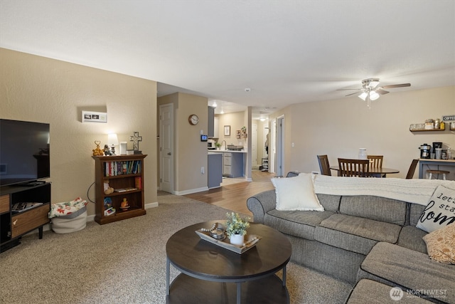 living room with baseboards, a ceiling fan, and carpet flooring