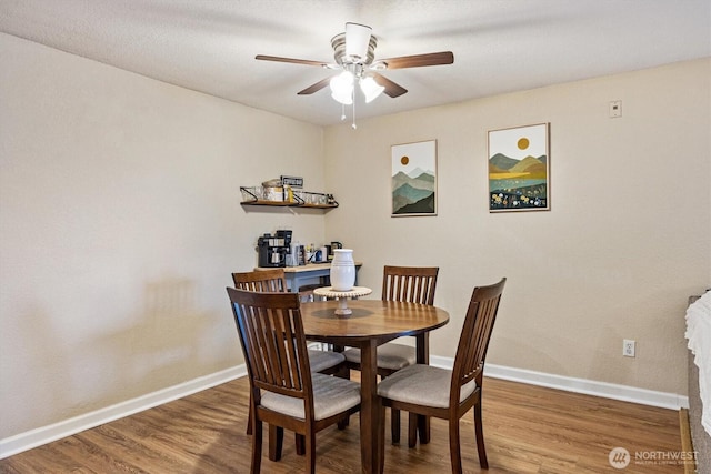 dining space with wood finished floors, a ceiling fan, and baseboards