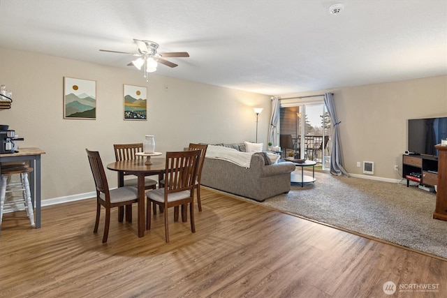 dining space with a ceiling fan, baseboards, visible vents, and wood finished floors