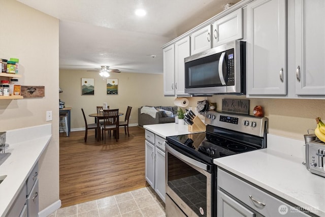 kitchen with appliances with stainless steel finishes, light countertops, baseboards, and a ceiling fan